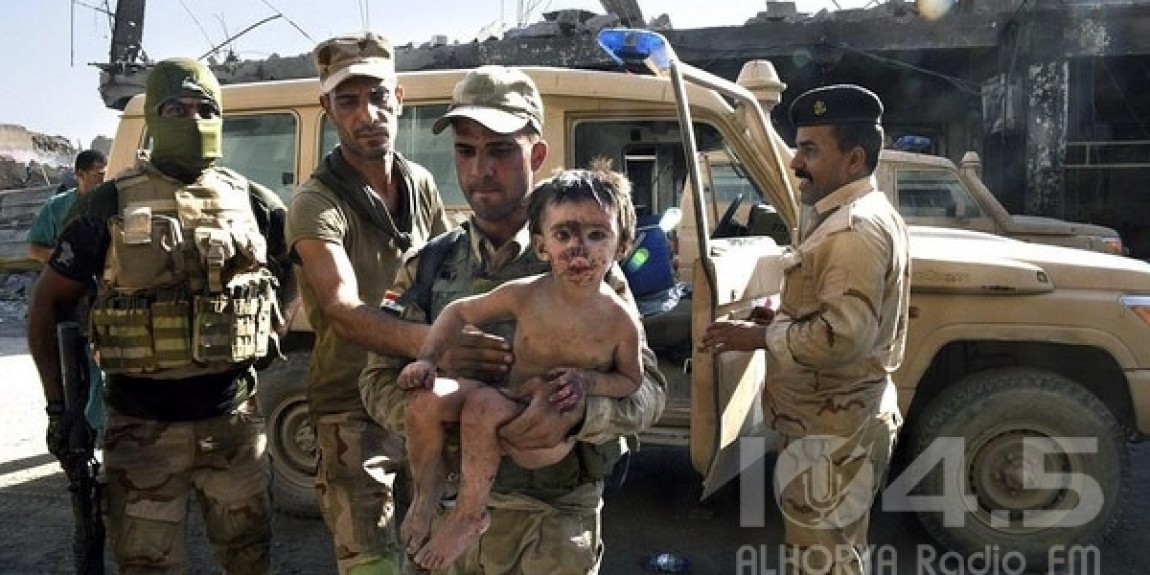 الجنود العراقيون يحملون الطفل الأول الذي وجد يحاول تناول قطعة لحم غير مطهية ليبقى على قيد الحياة